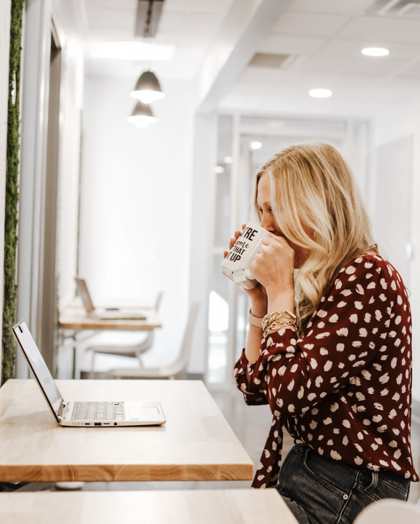 Freelancer drinking coffee from a mug with a sassy quote on it while coworking from a shared desk at Haven Collective